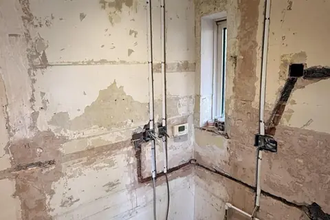 Bare plaster with new cable chases and back boxes during a rewire