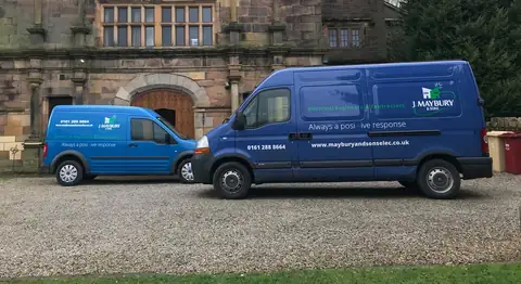 Two J Maybury vans parked outside an old stone building